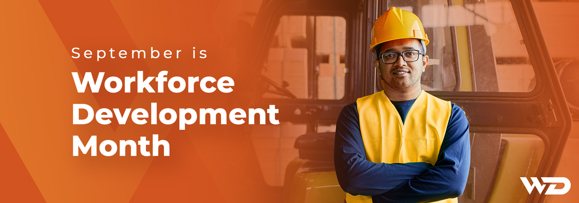 Worker wearing a yellow hard hat and safety vest standing with folded arms in front of a forklift in an industrial warehouse. Text on image reads: 'September is Workforce Development Month.' WD logo in lower right corner.